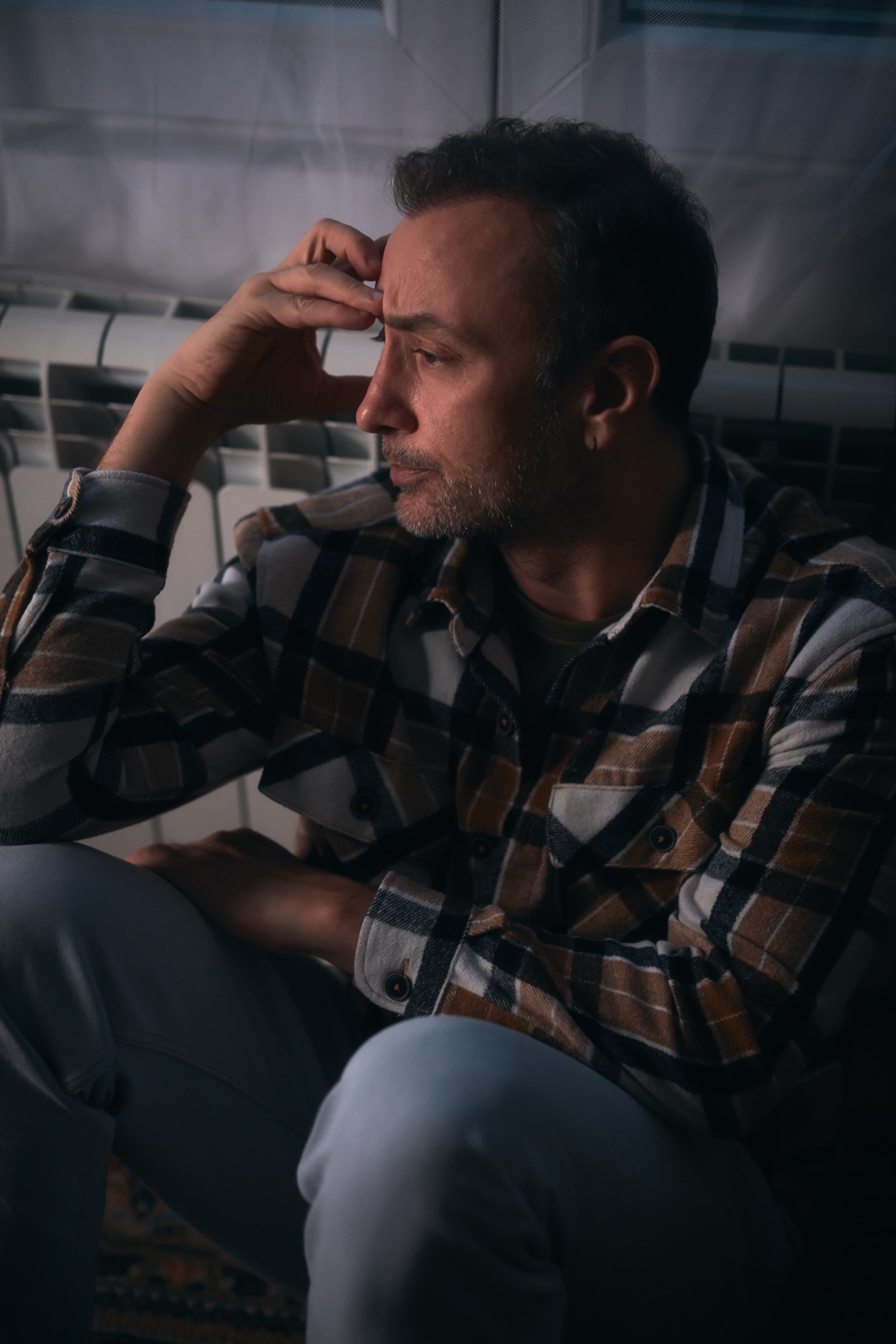 忧心忡忡的男子坐在地板上